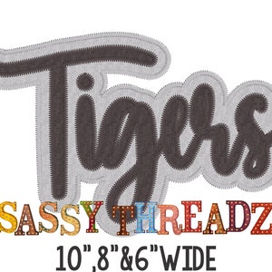 May include: A gray fabric applique with the word "Tigers" in black outlined lettering. Below the word "Tigers" is the text "SASSY THREADZ" in colorful block letters with light bulbs. The text "10, 8 & 6" WIDE is below the colorful letters.