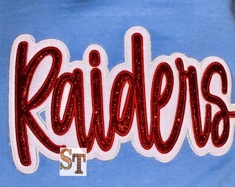 May include: Red glitter "Raiders" lettering with a white outline on a light blue background.