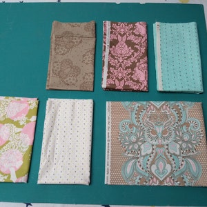 Peut inclure: Six échantillons de tissu avec différents motifs et couleurs. Les échantillons comprennent un tissu brun à motif floral, un tissu rose et brun à motif damassé, un tissu bleu clair à pois, un tissu vert à motif floral, un tissu blanc à pois et un tissu brun à motif paisley.