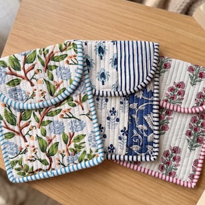 May include: Three rectangular quilted fabric pouches with rounded flaps. The left pouch features a green and blue floral vine pattern. The center pouch has a blue and white striped and floral design. The right pouch displays a pink floral print.