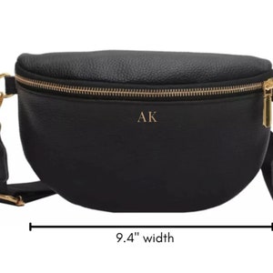 K&ouml;nnte beinhalten: Schwarze Leder-Bauchtasche mit goldfarbenem Rei&szlig;verschluss und goldfarbenen Beschl&auml;gen. Die Tasche ist 9,4 Zoll breit und 5,9 Zoll lang. Die Initialen "AK" sind auf der Vorderseite der Tasche gepr&auml;gt.
