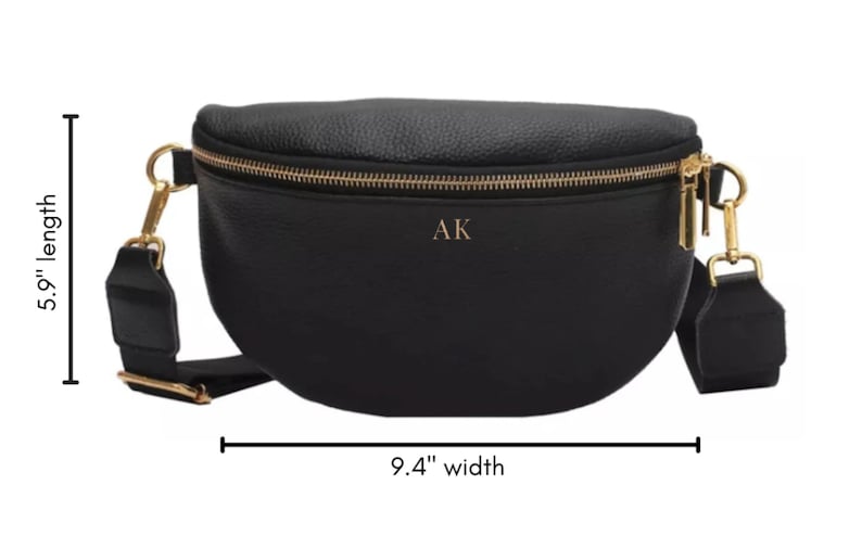 K&ouml;nnte beinhalten: Schwarze Leder-Bauchtasche mit goldfarbenem Rei&szlig;verschluss und goldfarbenen Beschl&auml;gen. Die Tasche ist 9,4 Zoll breit und 5,9 Zoll lang. Die Initialen "AK" sind auf der Vorderseite der Tasche gepr&auml;gt.