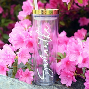 May include: A clear, reusable tumbler with a gold lid and a white straw. The tumbler has the name "Samantha" written on it in a cursive font.