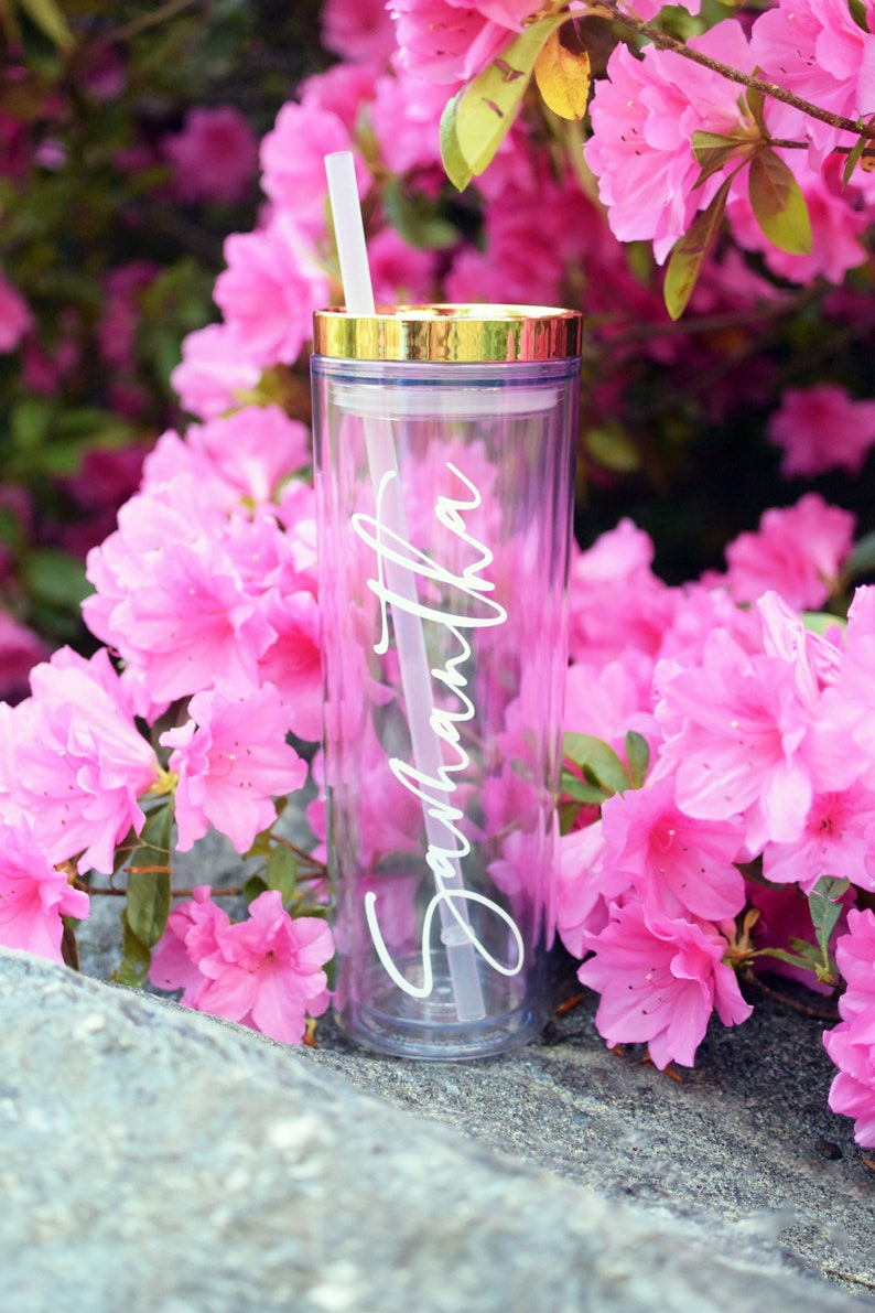 May include: A clear, reusable tumbler with a gold lid and a white straw. The tumbler has the name "Samantha" written on it in a cursive font.