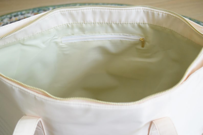 May include: A white canvas tote bag with a zippered pocket on the inside. The bag has two handles.