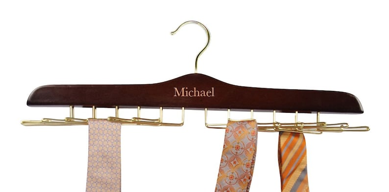 May include: A dark brown wooden tie hanger with a gold hook and metal tie clips. The hanger is personalized with the name "Michael".