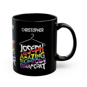 May include: Black coffee mug with a white design featuring the text "Joseph and the Amazing Technicolor Dreamcoat" with a rainbow color scheme. The mug also has the name "Christopher" printed on it.
