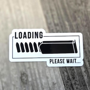 May include: A white sticker with a black and white graphic of a loading bar. The word "LOADING" is at the top, and "PLEASE WAIT..." is at the bottom. The sticker is rectangular with rounded corners.
