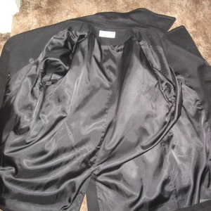May include: Black peacoat with a satin lining. The coat is unbuttoned and turned inside out, showing the lining.