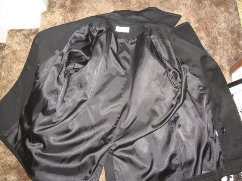 May include: Black peacoat with a satin lining. The coat is unbuttoned and turned inside out, showing the lining.