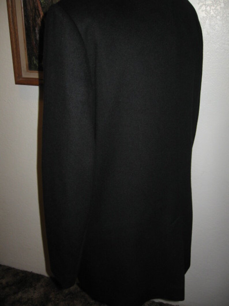 May include: A black blazer with a smooth, textured fabric. The blazer has a classic, tailored fit.