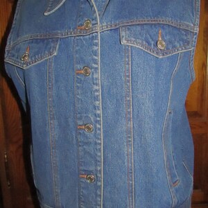 Op de afbeelding: Een blauwe denimvest met een knoopsluiting en twee zakken. De vest heeft een klassieke stijl en is gemaakt van duurzaam materiaal.