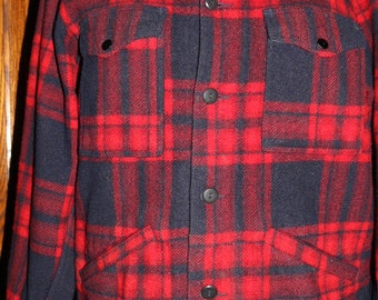 May include: A red and black plaid flannel shirt with a button-up front and two flap pockets.