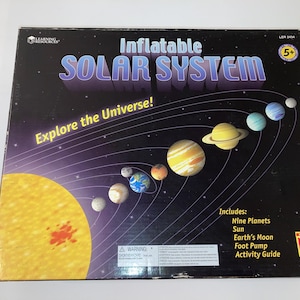 May include: An inflatable Solar System educational toy set. The box features a dark background with illustrations of planets and the sun. Text on the box reads "Inflatable Solar System" and "Explore the Universe!" Includes nine planets, sun, Earth's moon, foot pump, and activity guide.