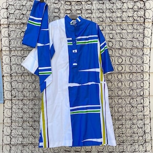May include: A white and blue geometric print dress with a matching blue sash. The dress has a high collar and short sleeves. The sash has green and white stripes.