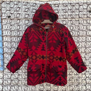May include: A red, black, and orange hooded jacket with a geometric pattern. The jacket has a zipper closure and two pockets.