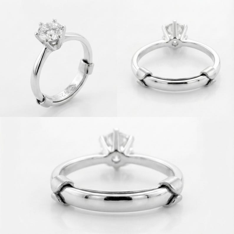 May include: A silver ring with a large, clear gemstone. The ring has a simple band with a decorative element on the sides. The ring is shown from multiple angles.