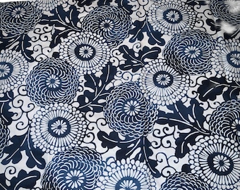 Könnte beinhalten: Ein Textilstoff mit einem sich wiederholenden Muster aus dunkelblauen Chrysanthemenblüten und stilisierten Blättern auf weißem Hintergrund. Das Design besteht aus dichten, kreisförmigen Blumenmotiven mit strahlenden Blütenblättern und Ranken.