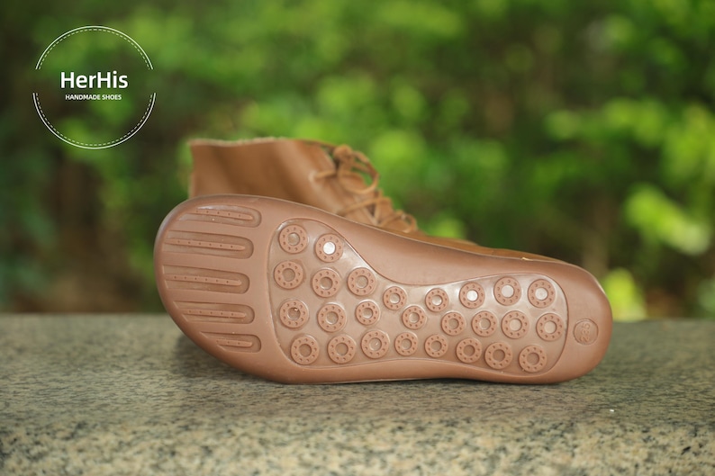 May include: Close-up of the brown leather sole of a brown leather boot. The sole has a textured pattern of small circles.