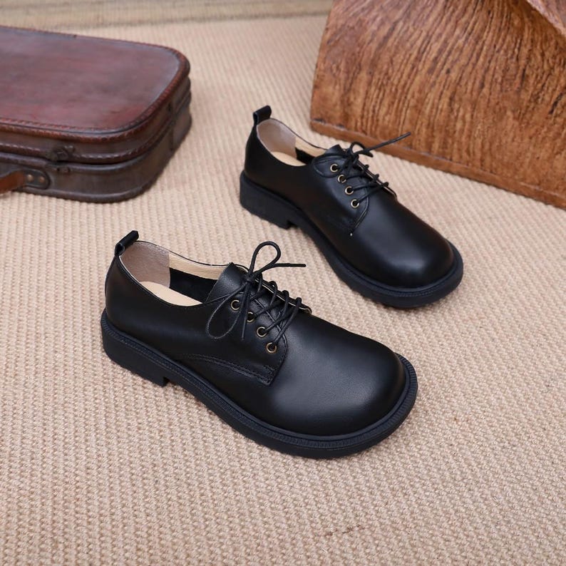 Puede incluir: Un par de zapatos negros de cuero con cordones y suela gruesa. Los zapatos tienen un estilo oxford cl&aacute;sico y son perfectos para el uso diario.