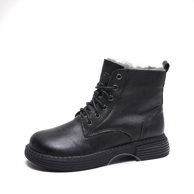 May include: Black leather ankle boots with a lace-up closure and a thick, textured sole. The boots have a warm, fuzzy lining.