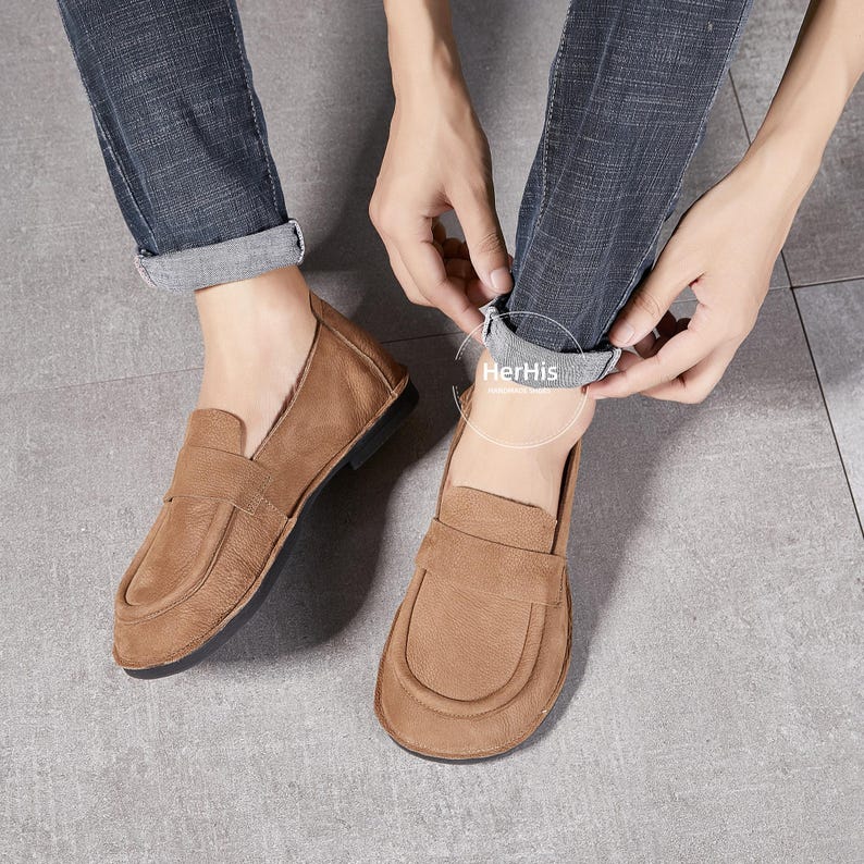 May include: A pair of brown leather loafers with a simple design. The loafers have a rounded toe and a slip-on style.