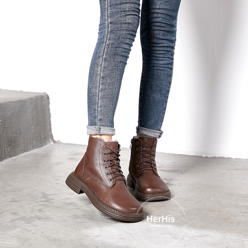 May include: Brown leather lace-up boots with a chunky sole. The boots are worn with blue jeans.
