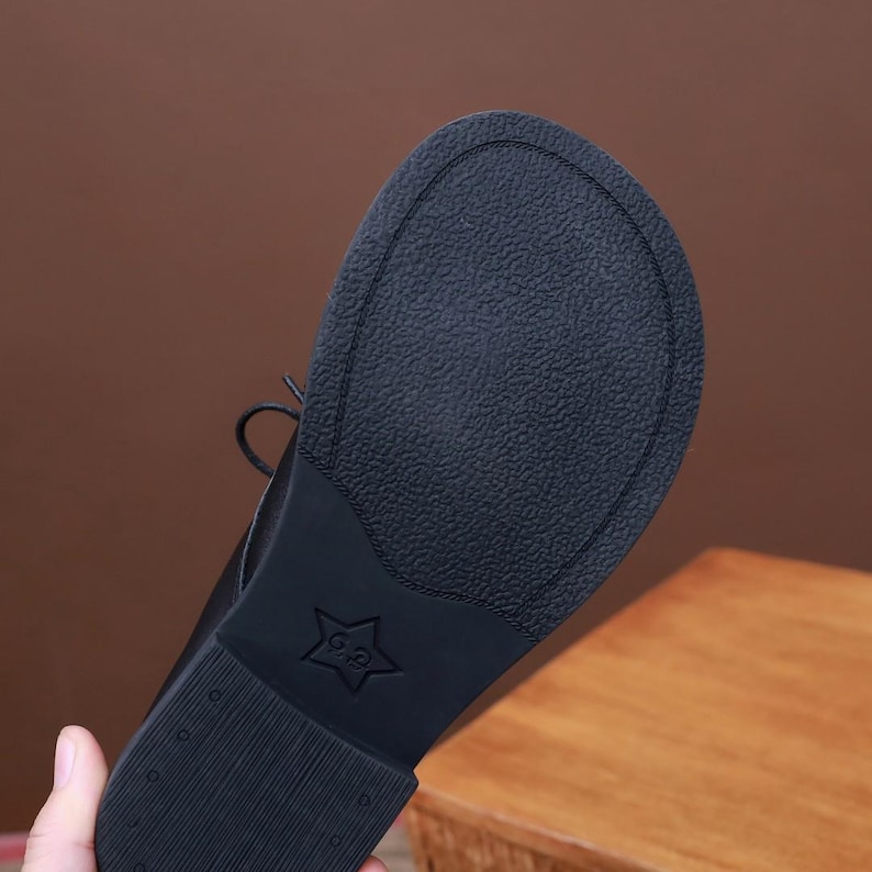 Puede incluir: Zapatos negros de cuero con cordones y suela de goma texturizada. La suela tiene una estrella con el texto "G&P" en su interior.