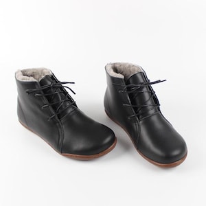 May include: A pair of black leather ankle boots with a lace-up fastening and a faux fur lining.