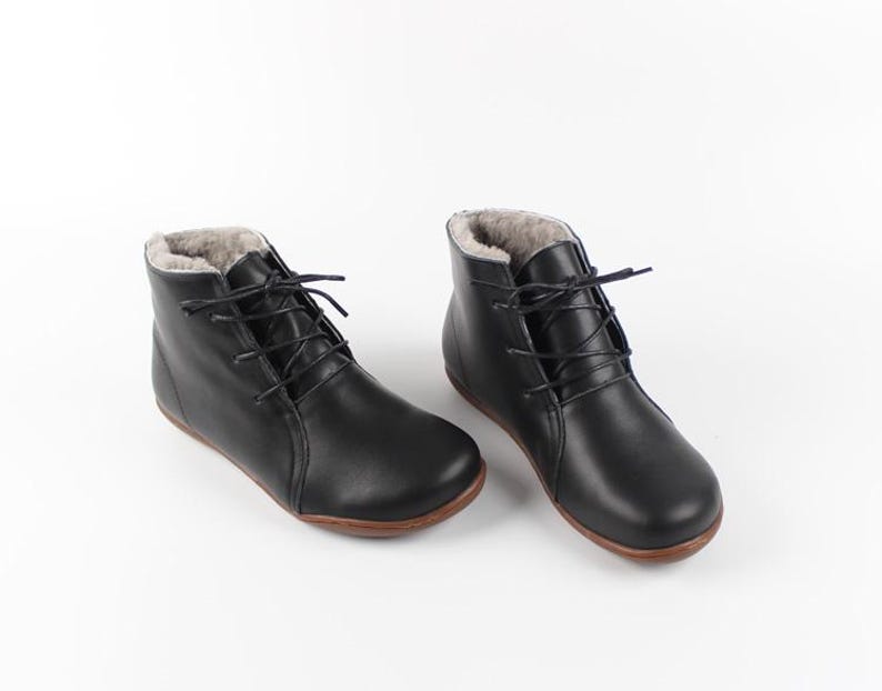 May include: A pair of black leather ankle boots with a lace-up fastening and a faux fur lining.