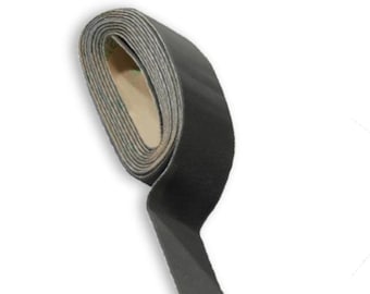 May include: A roll of black hook and loop tape, also known as Velcro, is shown rolled up with the hook side facing out.