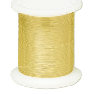 May include: A spool of golden-yellow thread, tightly wound around a white plastic core. The thread appears smooth and fine, suitable for sewing or crafting projects. The spool has a wide base and a flat top.