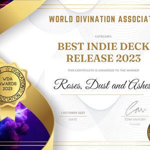 Może przedstawiać: Złoty certyfikat z białym tłem i czarnym tekstem. Certyfikat zawiera napis "World Divination Association" i "Best Indie Deck Release 2023". Certyfikat został przyznany dla "Roses, Dust and Ashes".