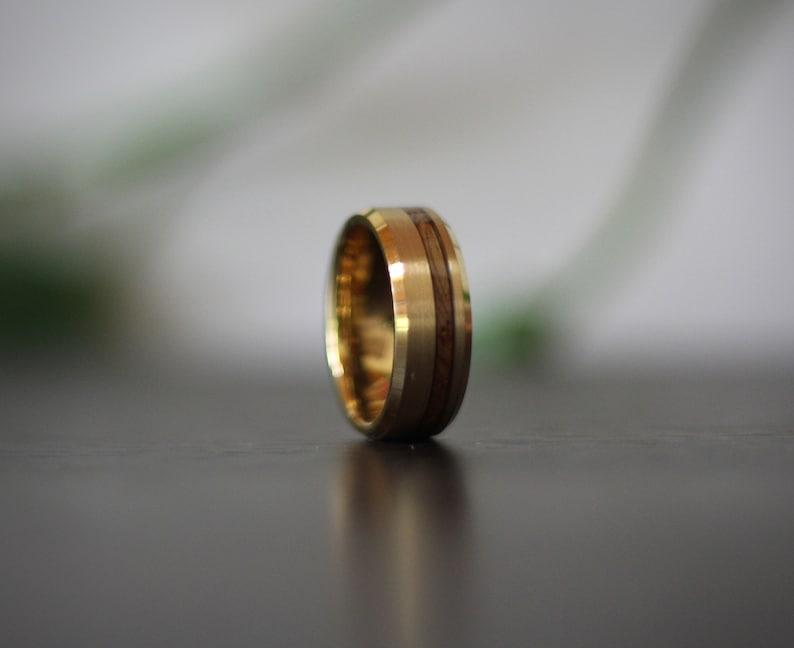 May include: A gold ring with a wood inlay. The ring is a simple design with a smooth finish.