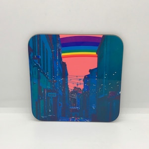 May include: A colorful rainbow arches over a narrow street lined with buildings. The street is decorated with string lights. The buildings are a dark blue color. The rainbow is a vibrant mix of red, orange, yellow, green, blue, indigo, and violet.