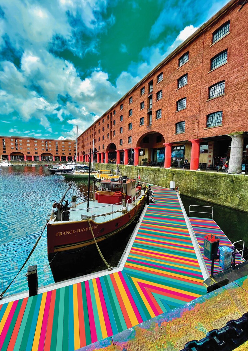 May include: A red and white boat named "France-Hayhurst" is docked at a waterfront with a colorful striped walkway leading to a brick building with arched doorways.