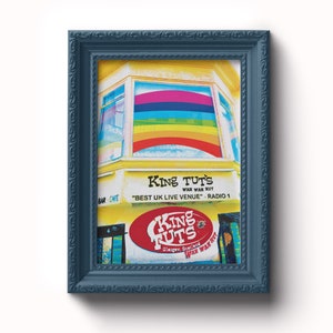 May include: A yellow building with a rainbow window and a red sign that says "King Tut's" with the text "Wah Wah Hut" and "Glasgow, Scotland" underneath. The sign also says "Best UK Live Venue" - Radio 1.
