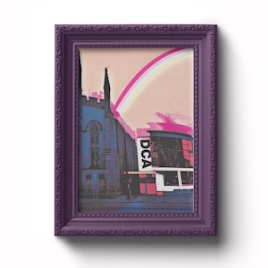 May include: A framed print of a building with a rainbow in the sky. The building is a church with a tall spire and a sign that says "DCA". The print is in a purple frame with a decorative border.