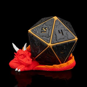May include: A black and gold d20 dice with a textured surface sits on a red dragon figurine. The dragon is curled up with its wings spread out.
