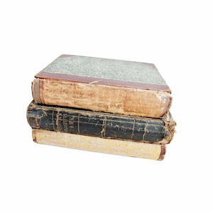 May include: A stack of three antique books with worn, textured covers. The top book has a faded green cover with a brown spine. The middle book is black, and the bottom book is a light tan color.