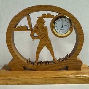May include: Wooden clock with a baseball player silhouette and a round clock face. The clock is on a wooden base.