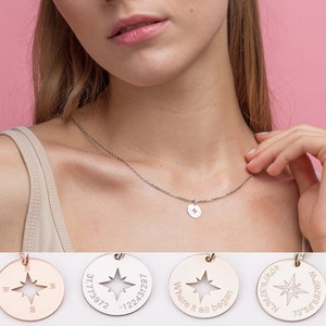 Può includere: Una collana d'argento con un ciondolo rotondo con un design a bussola con una stella al centro. Il ciondolo è inciso con il testo "Where it all began" e coordinate. La collana è indossata da una persona con i capelli lunghi e biondi.
