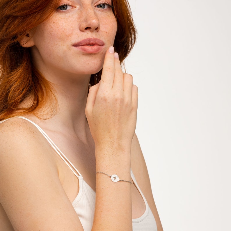 Puede incluir: Una pulsera de plata con un peque&ntilde;o dije circular con un corte de estrella.