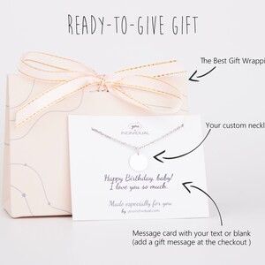 May include: A gift box with a white card and a silver necklace with a round pendant. The card has a message that says "Happy Birthday, baby! I love you so much. Made especially for you by youindividual.com".