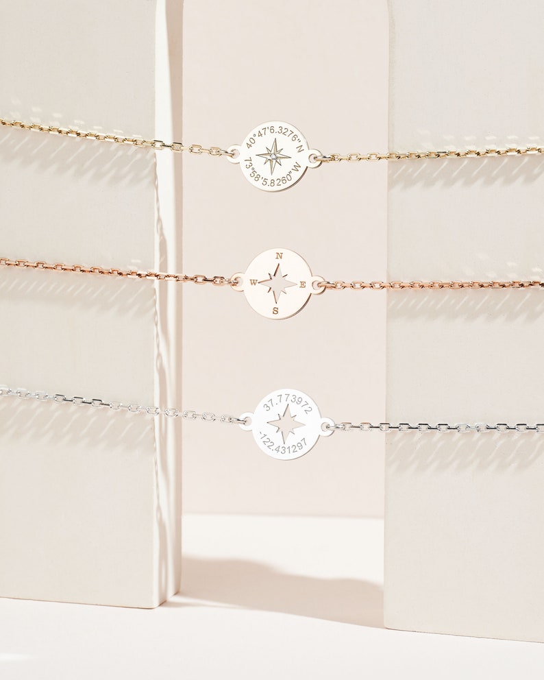 Puede incluir: Tres pulseras de plata con dijes de br&uacute;jula. Cada dije tiene una rosa de los vientos y coordenadas. El dije superior tiene las coordenadas "40.476.3276&deg;N 73.58.5.8260&deg;W". El dije del medio tiene una rosa de los vientos con las direcciones N, E, S y W. El dije inferior tiene las coordenadas "37.773972 -122.431297".