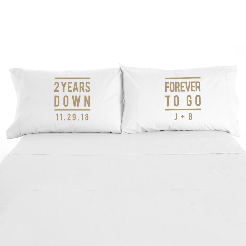 May include: Two white pillowcases with brown text. The pillowcase on the left says "2 Years Down 11.29.18". The pillowcase on the right says "Forever To Go J + B".