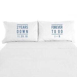 May include: Two white pillowcases with blue text. The left pillowcase says "2 Years Down 11.29.18". The right pillowcase says "Forever To Go J + B".
