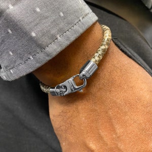 Peut inclure: Un bracelet en cuir marron clair avec un fermoir argenté. Le fermoir porte l'inscription "South Bena" gravée.