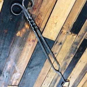 May include: A pair of black metal fireplace tongs with a twisted handle and a heart-shaped design at the end.