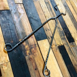 May include: A pair of black metal tongs with twisted handles. The tongs are made of forged steel and have a rustic look. They are perfect for grabbing hot items from a fire or grill.